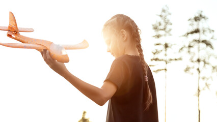 Playful girl kid run with airplane on background amazing summer warm sunset. Dream freedom concept. Child runs on field holding in hands toy aircraft