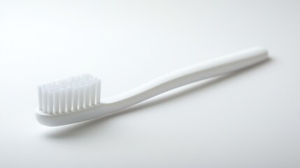 A simple white toothbrush lying on a white surface in a well lit and minimalist setting style shot