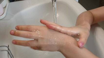 Child washes hands in the sink. A little girl opens the water, washes her hands, closes the water  - Powered by Adobe