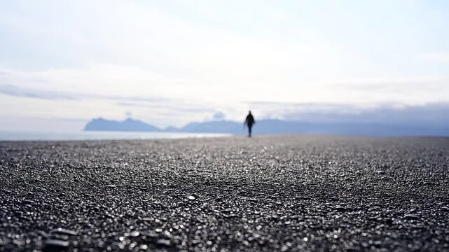 Hvalnes Nature Reserve Beach in Iceland - Silhouette of person walking on the black pebble beach