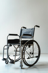 Modern wheelchair with sleek design and black upholstery, positioned on a light wooden floor against a minimalistic background, symbolizing mobility and independence. Vertical poster