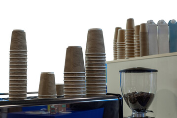 Stacks of textured paper coffee cups near espresso machine