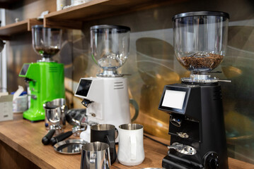 Coffee grinders on wooden counter with pitchers and beans