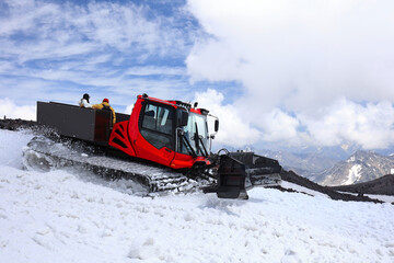 Red Snowcat (Snow Groomer) With Passengers Driving On A Snowy Mountain Slope. Preparing Ski Trails....
