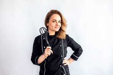 young beautiful woman chef in black uniform with a whisk on a white background