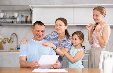 Happy adult man reading notification from employer informing of promotion or awarding bonus for...