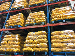 Pallets of 50 pound onion sacks stacked in distribution centre ready for shipment to supermarkets