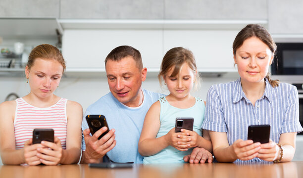 Portrait of happy children and parents using phones at home