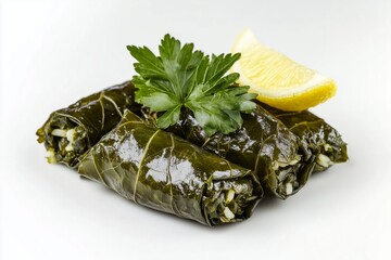 Vine leaves stuffed with rice and herbs served with lemon wedges on a white background