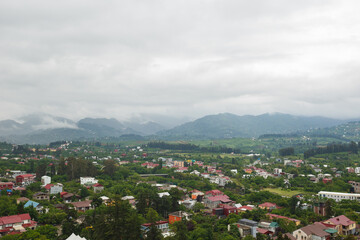 Green mountain landscape with scattered village houses and low clouds in the sky