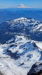 Snowy mountain peaks under a clear blue sky with a distant snow capped mountain in the background