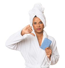 Young Filipino woman with sponge showing a dislike gesture, thumbs down. Disagreement concept.