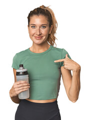 Blonde athlete with water bottle person pointing by hand to a shirt copy space, proud and confident