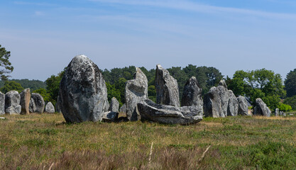 Alignement de pierres préhistoriques, les menhirs de Carnac, sous un ciel bleu.