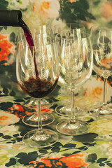  Red wine is poured into a glass from a bottle