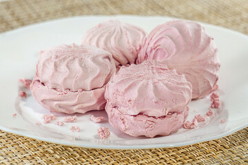 Pink marshmallows lie on a white plate