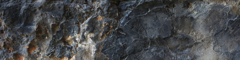 Close-up of dark volcanic stone with uneven surface.Wide view.Ideal for use in design, 3D modeling, game environments, and architectural backgrounds.High quality. Copy space. 