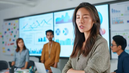 Confident female professional presenting financial charts and trends during corporate meeting in modern office with big screens, business strategy and data analytics concept video for leadership brand - Powered by Adobe