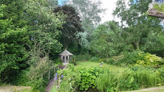 Malpas Cheshire England UK. 01.06.2025. Video, An beauitful English country garde with trees on boundary and a summer house.