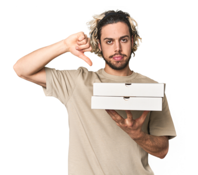 Young man holds pizza boxes for delivery showing a dislike gesture, thumbs down. Disagreement concept.