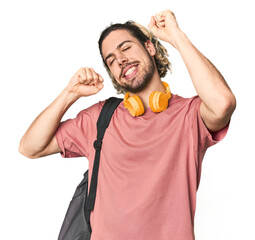 Young student with backpack and headphones celebrating a special day, jumps and raise arms with...