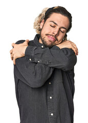 Young Caucasian man in studio setting hugs, smiling carefree and happy.
