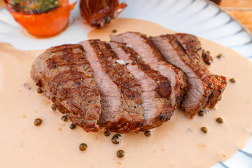 Juicy grilled steak served with pepper sauce and garnished with roasted vegetables at a rustic dining setting	