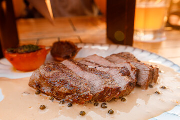 Delicious grilled steak with creamy sauce and herbs on a rustic wooden table at sunset	