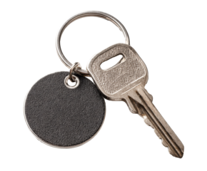 A metal key is attached to a keychain with a round tag on a transparent background, cut out