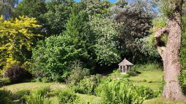 Malpas Cheshire England UK. 01.06.2025. Video, An beauitful English country garde with trees on boundary and a summer house.