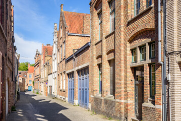 Old brick terraced houses along a narrow cobbled street in a city centre on a sunny summer day