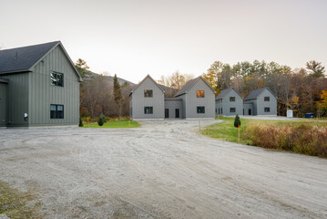 Semi-detached houses under construction in a housing development surrounded by woodland in the mountains at sunset in autumn