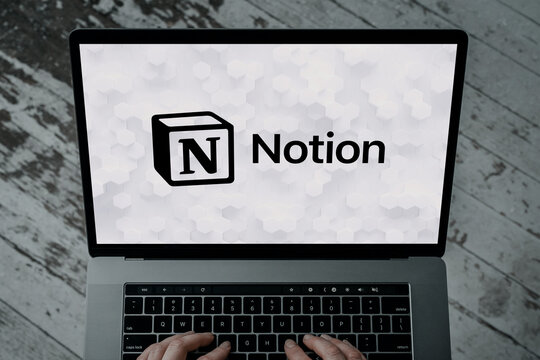Hands typing on laptop keyboard showing notion app interface