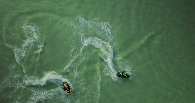 Couple of jet skis side by side speeding across beautiful turquoise lake surface, drone shot