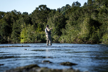 Man Fly Fishing in Shallow River Waters
