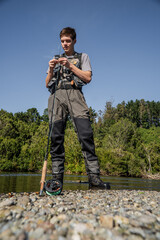 Young Man Preparing Fishing Rod by the River