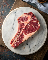 Freshly cut t-bone steak presented on a round marble plate, showcasing its juicy marbling and rich color