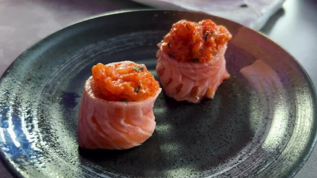 Sushi and rolls in plate. Close-up of sushi rolls on rectangle sushi plate. A set of fresh sushi rolls with salmon, avocado and black sesame seeds served on a plate with chopsticks. Japanese seafood 