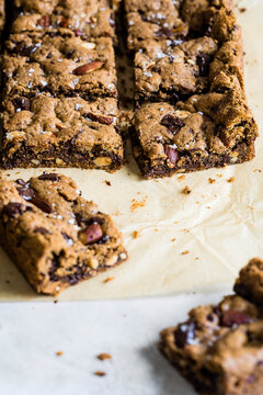 Close-up of chocolate chip cookie bars with nuts on parchment paper.