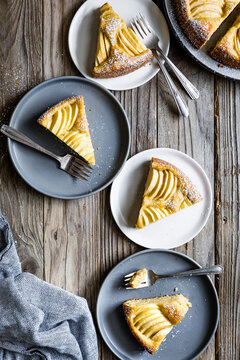 Slices of apple cake on ceramic plates with forks on a wooden table.