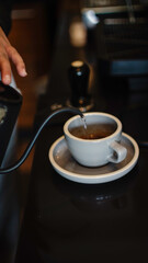 Pouring hot water into a cup on café counter to make hot coffee