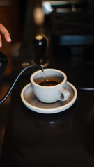 Pouring hot water into a cup on café counter to make hot coffee