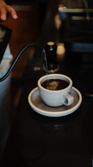 Pouring hot water into a cup on café counter to make hot coffee