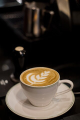 A cup of hot latte with froth art on café counter