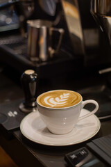 A cup of hot latte with froth art on café counter