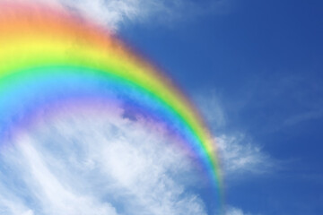 Bright rainbow in blue sky with clouds on sunny day