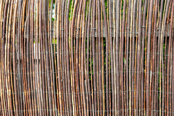 fence made of small willow trees combined to a textured mat