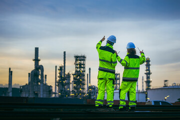 Back View of Engineers Showing Thumbs Up at an Industrial Plant at Dusk, Two Industrial Workers Collaborating On-Site, Professional Engineers Overseeing Operations at a Refinery