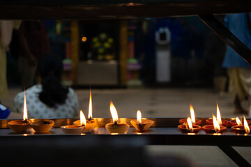 Oil Candles Lit Up In The Backgroundpeople Praying At An Indian Temple