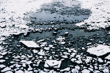 Snow covered rocks on the side of a river in New Zealand.